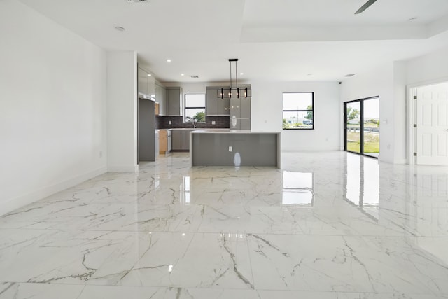 418 NE 31st Ter, Cape Coral, FL 33909 - unfurnished living room with plenty of natural light, baseboards, recessed lighting, light marble finish flooring, and a sink