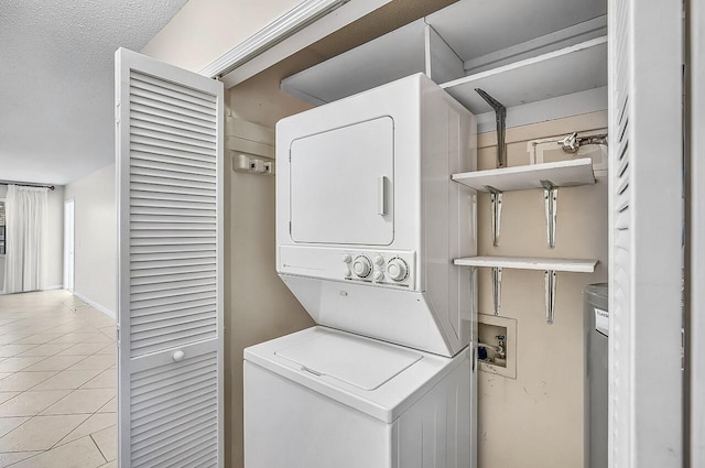 1801 Indian River Blvd Unit B8, Vero Beach, FL 32960 - washroom with estacked washer and dryer, light tile patterned flooring, baseboards, and a textured ceiling