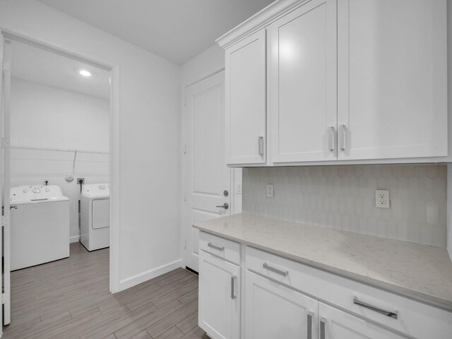3181 Streng Ln, Royal Palm Beach, FL 33411 - kitchen with washer and dryer, light stone counters, light wood-style floors, white cabinetry, and baseboards