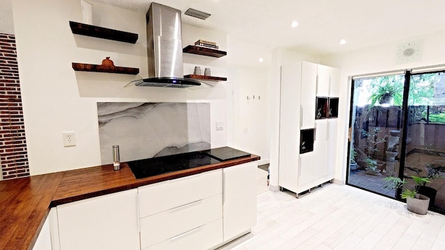 4344 Carambola Cir Unit F707, Coconut Creek, FL 33066 - kitchen featuring open shelves, wall chimney range hood, black electric cooktop, butcher block countertops, and white cabinets