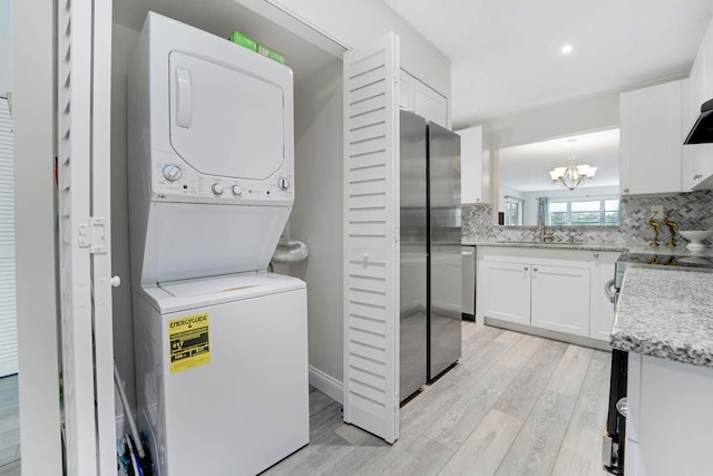 5890 Sugar Palm Ct Unit E, Delray Beach, FL 33484 - laundry room featuring stacked washing machine and dryer, a chandelier, and light wood-style floors