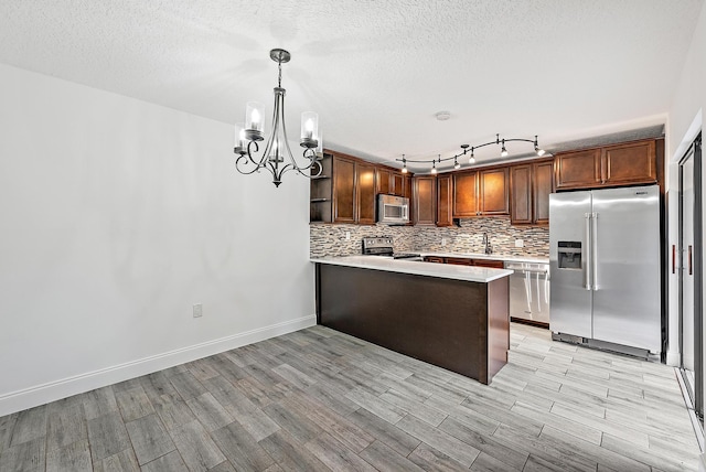 1021 10th Ct Unit 1021, Palm Beach Gardens, FL 33410 - kitchen with appliances with stainless steel finishes, a chandelier, light countertops, tasteful backsplash, and a peninsula
