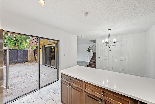1021 10th Ct Unit 1021, Palm Beach Gardens, FL 33410 - kitchen with a chandelier, light countertops, pendant lighting, a textured ceiling, and light wood-style floors