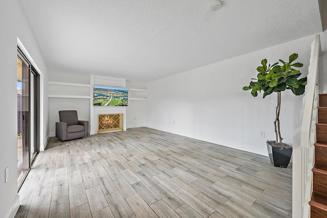 1021 10th Ct Unit 1021, Palm Beach Gardens, FL 33410 - unfurnished living room featuring wood finished floors, a textured ceiling, a lit fireplace, and baseboards