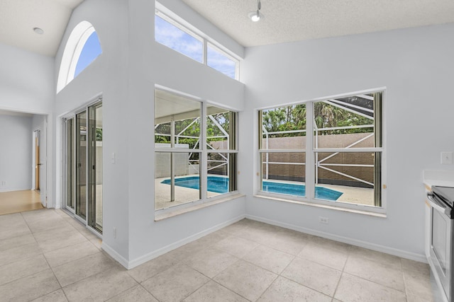 2281 SW Olympic Club Ter, Palm City, FL 34990 - unfurnished dining area with light tile patterned floors, a towering ceiling, baseboards, and a textured ceiling