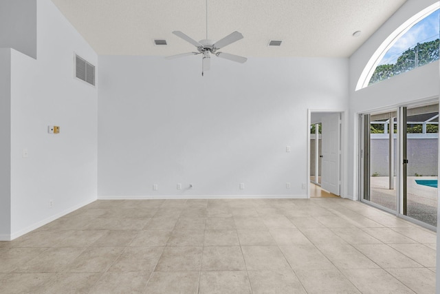 2281 SW Olympic Club Ter, Palm City, FL 34990 - spare room with a towering ceiling, a ceiling fan, a textured ceiling, light tile patterned floors, and baseboards