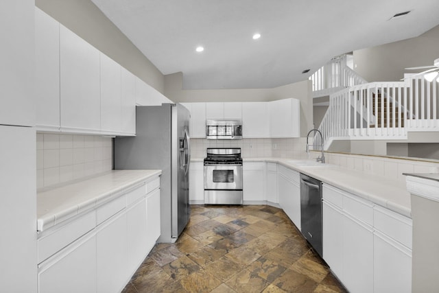 2274 SW Olympic Club Ter, Palm City, FL 34990 - kitchen featuring stainless steel appliances, a sink, stone tile floors, backsplash, and white cabinets