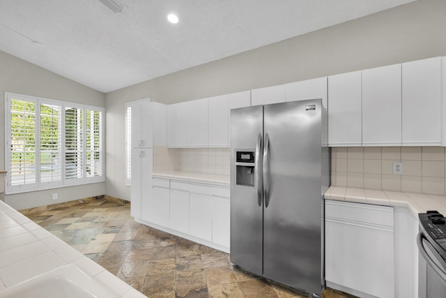 2274 SW Olympic Club Ter, Palm City, FL 34990 - kitchen with stainless steel fridge with ice dispenser, tile counters, vaulted ceiling, decorative backsplash, and white cabinets