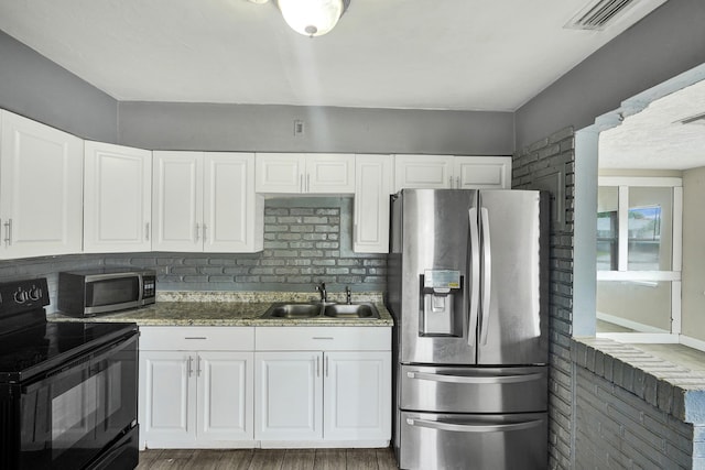 4701 N Andrews Ave, Oakland Park, FL 33309 - kitchen with stainless steel appliances, a sink, wood finished floors, and white cabinets