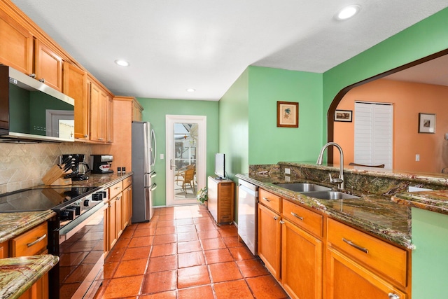 333 SE Dalva Ave, Port Saint Lucie, FL 34984 - kitchen featuring appliances with stainless steel finishes, a sink, decorative backsplash, arched walkways, and dark stone countertops