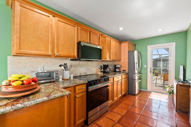 333 SE Dalva Ave, Port Saint Lucie, FL 34984 - kitchen with appliances with stainless steel finishes, tasteful backsplash, recessed lighting, stone counters, and brown cabinetry
