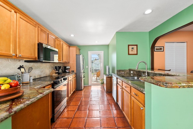 333 SE Dalva Ave, Port Saint Lucie, FL 34984 - kitchen featuring stainless steel appliances, a sink, backsplash, arched walkways, and dark stone counters