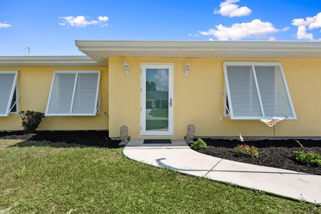 333 SE Dalva Ave, Port Saint Lucie, FL 34984 - view of exterior entry featuring stucco siding and a lawn