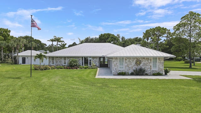 386 NE Ficus Ter, Jensen Beach, FL 34957 - view of front facade with stone siding, a front lawn, and metal roof