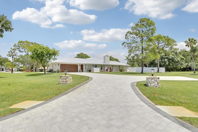 386 NE Ficus Ter, Jensen Beach, FL 34957 - ranch-style house with curved driveway, a garage, a chimney, and metal roof