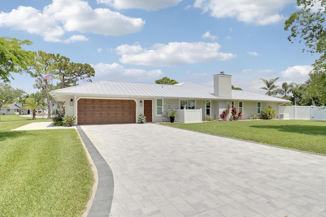 386 NE Ficus Ter, Jensen Beach, FL 34957 - ranch-style home with an attached garage, decorative driveway, a chimney, metal roof, and stucco siding