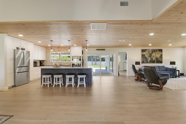386 NE Ficus Ter, Jensen Beach, FL 34957 - kitchen featuring appliances with stainless steel finishes, wood ceiling, a breakfast bar area, open floor plan, and white cabinets