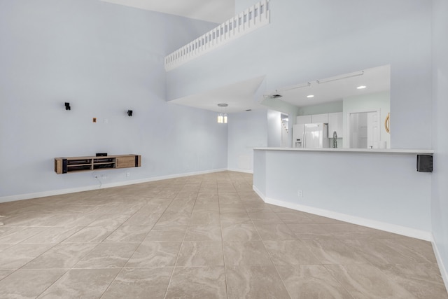 10125 N Military Trl, Palm Beach Gardens, FL 33410 - unfurnished living room featuring a sink, baseboards, and a towering ceiling