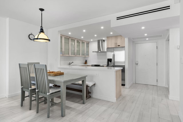 2301 Collins Ave Unit 1239, Miami Beach, FL 33139 - kitchen with wall chimney range hood, stainless steel refrigerator with ice dispenser, recessed lighting, glass insert cabinets, and light countertops