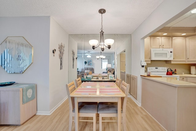 3561 Tall Pine Way Unit B-1, Greenacres, FL 33463 - dining room with light wood-type flooring, a chandelier, a textured ceiling, and baseboards