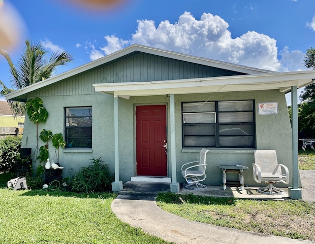 1109 W 26th St, West Palm Beach, FL 33409 - view of front of property featuring stucco siding, a front yard, and covered porch
