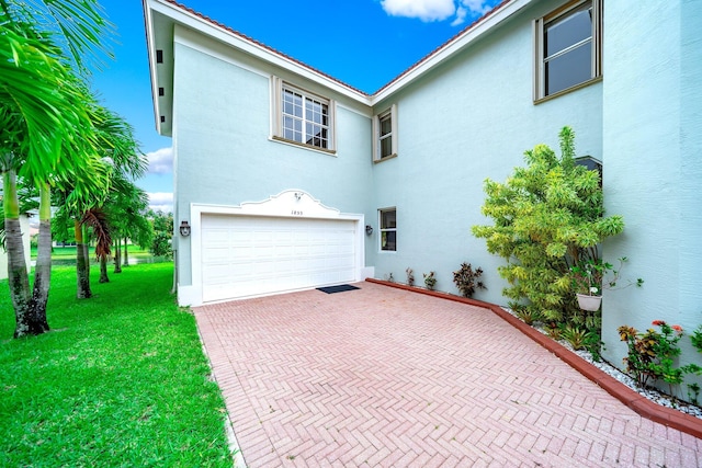 1855 SW Jamesport Dr, Port Saint Lucie, FL 34953 - view of front of home featuring a garage, stucco siding, a front yard, and decorative driveway