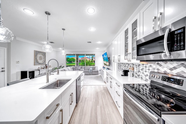 1855 SW Jamesport Dr, Port Saint Lucie, FL 34953 - kitchen featuring appliances with stainless steel finishes, a sink, light countertops, ornamental molding, and white cabinetry