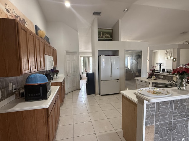 416 SE Calmoso Dr, Port Saint Lucie, FL 34983 - kitchen with white appliances, light countertops, brown cabinetry, and light tile patterned floors
