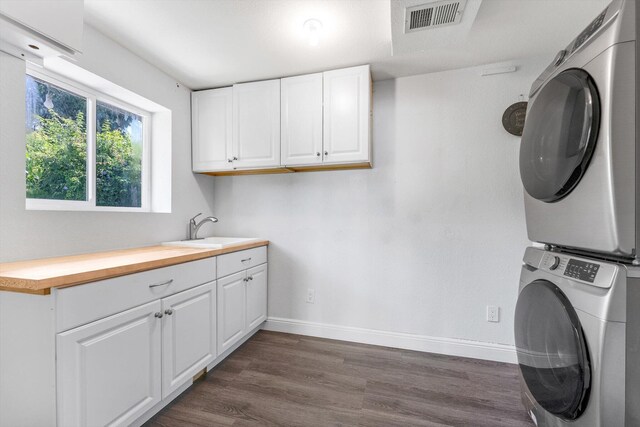 18905 Cloud Lake Cir, Boca Raton, FL 33496 - laundry area featuring stacked washer and clothes dryer, cabinet space, dark wood-type flooring, and baseboards