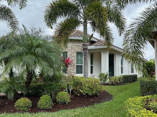 9624 SW Royal Poinciana Dr, Port Saint Lucie, FL 34987 - view of side of property featuring stucco siding, a yard, stone siding, and a tiled roof