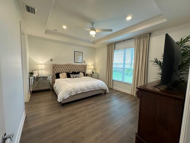 9624 SW Royal Poinciana Dr, Port Saint Lucie, FL 34987 - bedroom with a tray ceiling, dark wood-style flooring, baseboards, crown molding, and recessed lighting