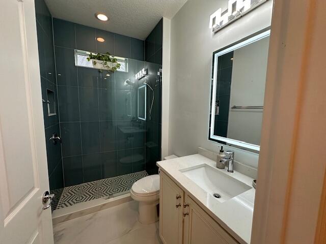 9624 SW Royal Poinciana Dr, Port Saint Lucie, FL 34987 - bathroom featuring tiled shower, toilet, vanity, a textured ceiling, and recessed lighting