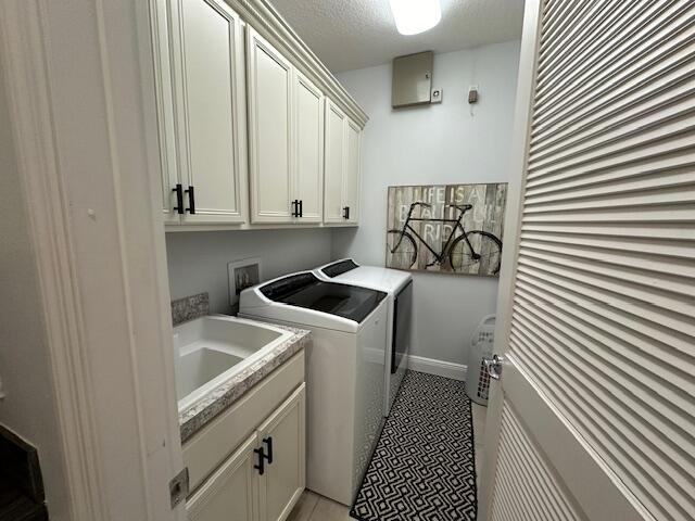 9624 SW Royal Poinciana Dr, Port Saint Lucie, FL 34987 - laundry room featuring washing machine and dryer, cabinet space, baseboards, and a textured ceiling