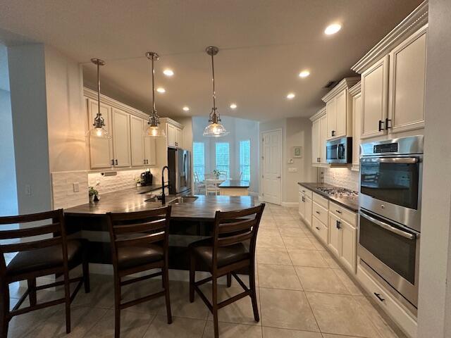 9624 SW Royal Poinciana Dr, Port Saint Lucie, FL 34987 - kitchen with stainless steel appliances, recessed lighting, tasteful backsplash, a peninsula, and dark countertops