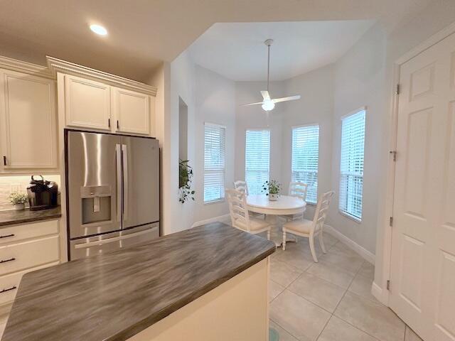 9624 SW Royal Poinciana Dr, Port Saint Lucie, FL 34987 - kitchen with stainless steel refrigerator with ice dispenser, dark countertops, a ceiling fan, light tile patterned floors, and baseboards