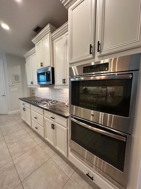 9624 SW Royal Poinciana Dr, Port Saint Lucie, FL 34987 - kitchen featuring appliances with stainless steel finishes, dark countertops, backsplash, light tile patterned flooring, and lofted ceiling