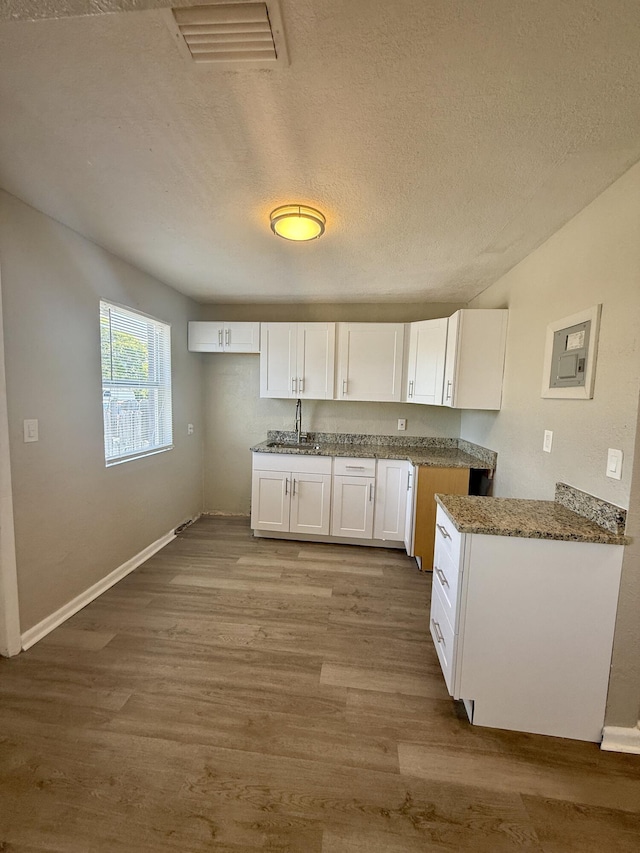 172 W 15th St, Riviera Beach, FL 33404 - kitchen featuring wood finished floors, a sink, white cabinets, a textured ceiling, and baseboards