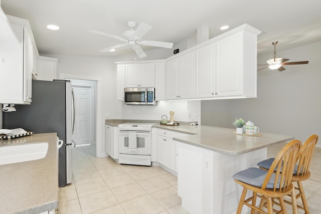 10453 SW Stratton Dr, Port Saint Lucie, FL 34987 - kitchen featuring appliances with stainless steel finishes, a ceiling fan, a peninsula, light tile patterned flooring, and a breakfast bar area