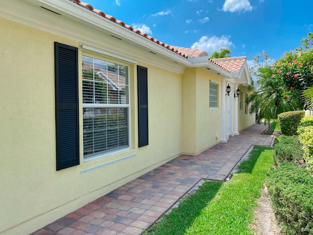 10453 SW Stratton Dr, Port Saint Lucie, FL 34987 - view of side of property with a patio, stucco siding, and a tiled roof