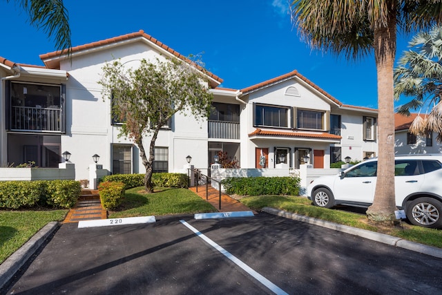 9717 Sills Dr E Unit 103, Boynton Beach, FL 33437 - view of front of home featuring a tile roof, uncovered parking, and stucco siding