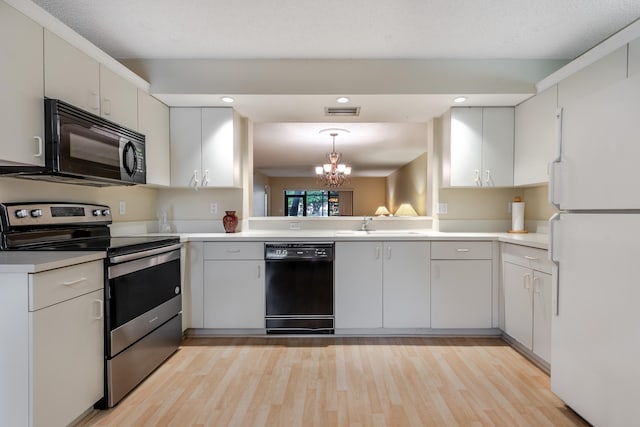9717 Sills Dr E Unit 103, Boynton Beach, FL 33437 - kitchen with black appliances, light wood-type flooring, a chandelier, light countertops, and recessed lighting
