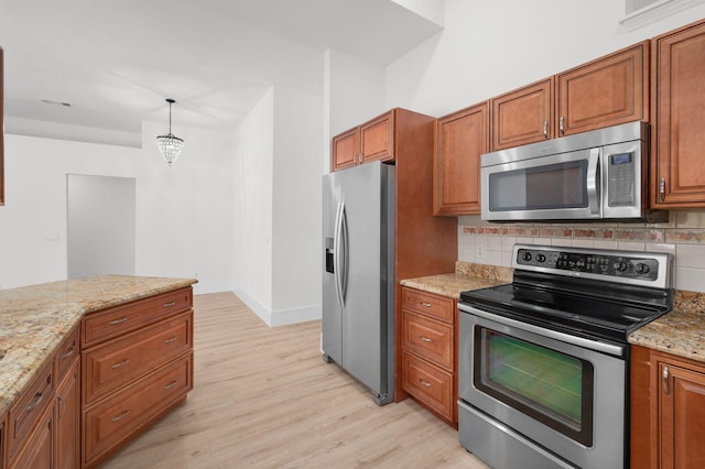 2707 SE Rawlings Rd, Port Saint Lucie, FL 34952 - kitchen with appliances with stainless steel finishes, light wood finished floors, brown cabinets, and backsplash