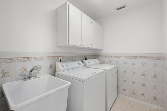 2707 SE Rawlings Rd, Port Saint Lucie, FL 34952 - laundry area with separate washer and dryer, tile walls, cabinet space, wainscoting, and light tile patterned floors