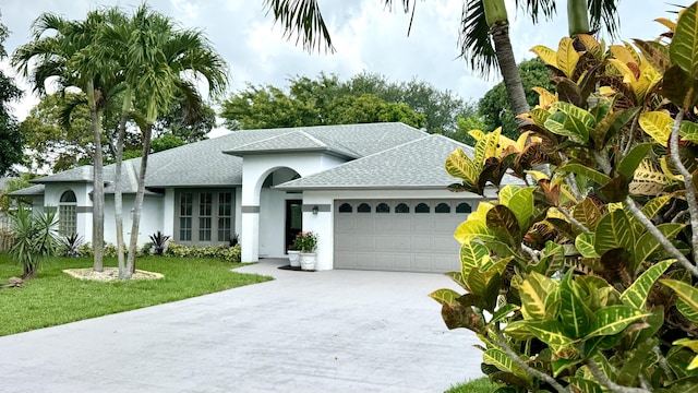 2707 SE Rawlings Rd, Port Saint Lucie, FL 34952 - view of front of home with roof with shingles, a garage, driveway, a front lawn, and stucco siding