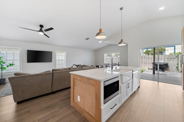 2540 NW 80th Ave, Margate, FL 33063 - kitchen featuring stainless steel microwave, vaulted ceiling, a sink, healthy amount of natural light, and light countertops
