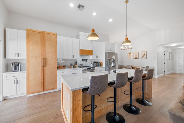2540 NW 80th Ave, Margate, FL 33063 - kitchen featuring appliances with stainless steel finishes, vaulted ceiling, an island with sink, tasteful backsplash, and light wood-style flooring