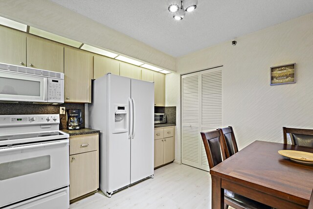 3400 S Ocean Blvd Unit 4H, Highland Beach, FL 33487 - kitchen with white appliances, light wood-style floors, dark countertops, and decorative backsplash