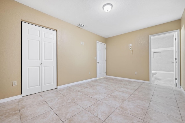 1332 SW G, Belle Glade, FL 33430 - unfurnished bedroom featuring light tile patterned floors, a closet, baseboards, and connected bathroom