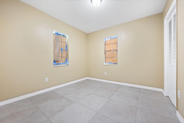 1332 SW G, Belle Glade, FL 33430 - unfurnished bedroom featuring a closet, light tile patterned floors, baseboards, and a textured ceiling