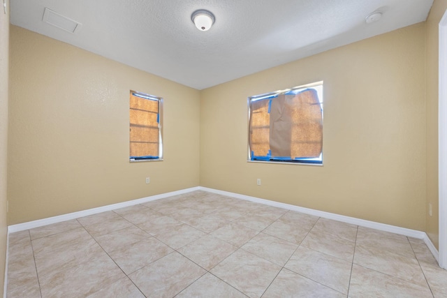 1332 SW G, Belle Glade, FL 33430 - unfurnished room with healthy amount of natural light, light tile patterned floors, a smoke detector, a textured ceiling, and baseboards